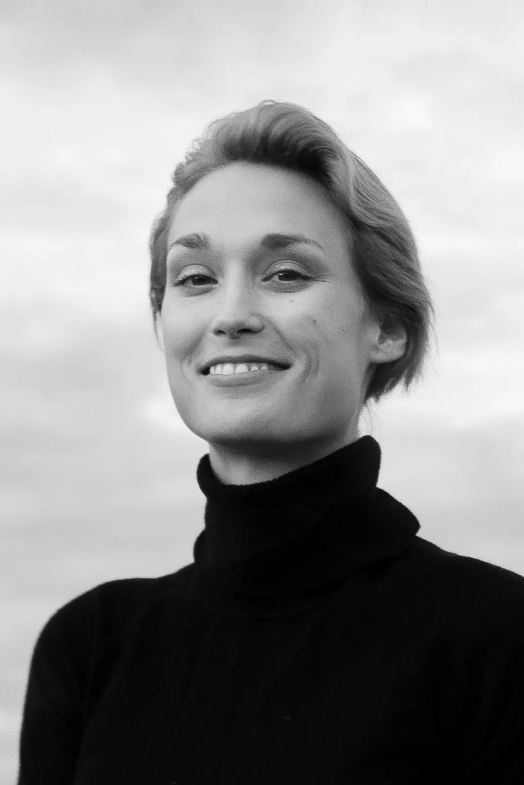 Deborah Muriel Blum outdoors in a black turtleneck, natural light, smiling
