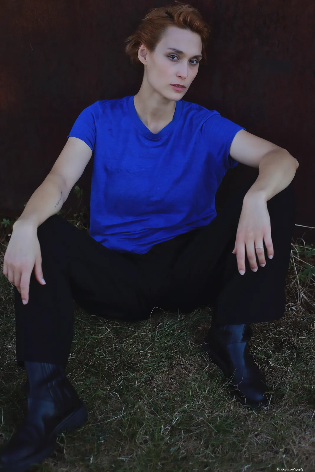 Deborah Muriel Blum seated on grass in a blue shirt and boots