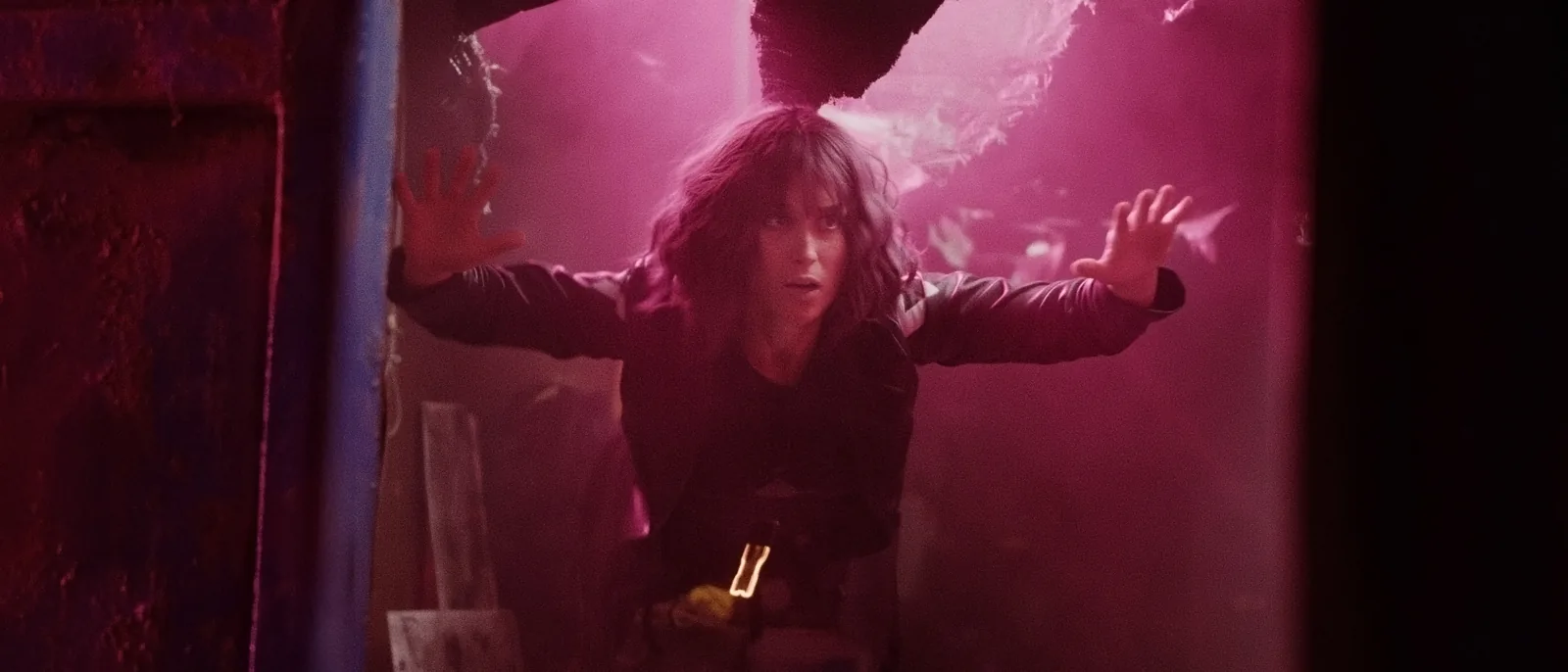 Actor Deborah Muriel Blum performing an action scene in a dramatic cyberpunk setting, captured mid-fall through a neon-lit industrial container